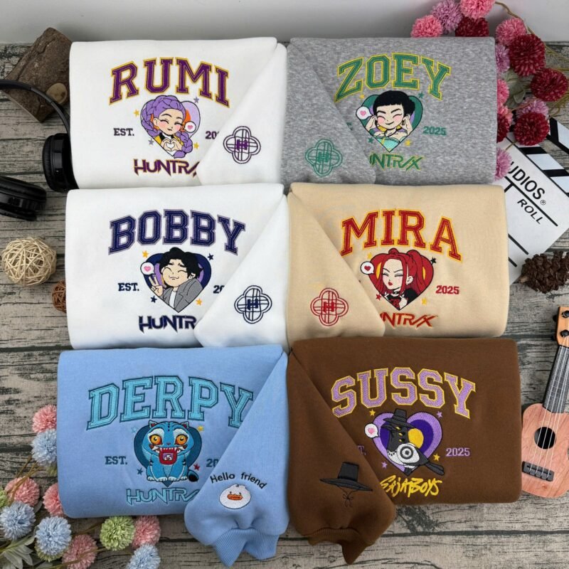 Pulls couple brodés KPop Demon Hunters : Rumi, Zoey, Bobby, Mira, Derpy et Sussy sur sweatshirts assortis, détails brodés sur la manche